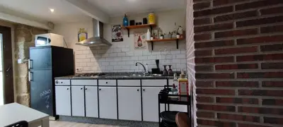 a kitchen with white cabinets and a brick wall at O Recuncho do Lito