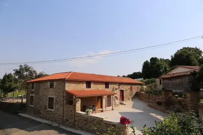 an old stone house with a red roof at O'Regueiro