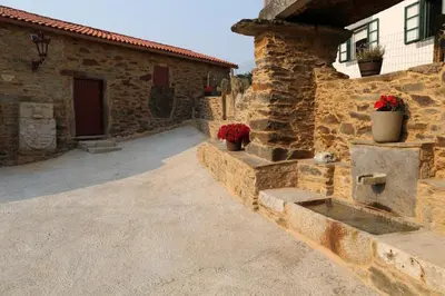 a stone house with a pathway to a building at O'Regueiro