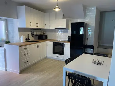 a kitchen with white cabinets and a table with chairs at Fogar en Soutelo in Forcarei