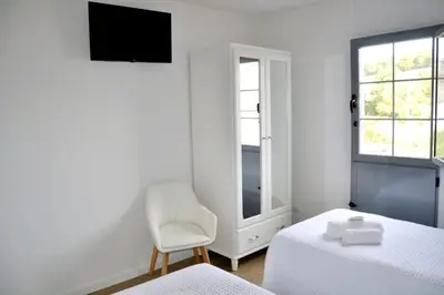 a bedroom with two beds and a chair and a television at Encanto de Oscos in San Martín de Oscos