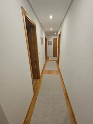 a hallway with white walls and wooden doors and a rug at Natalia in Allariz
