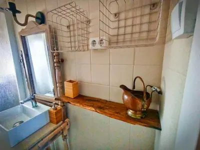 a bathroom with a sink and a pot on a shelf at A Casiña do Anselmiño in Celanova