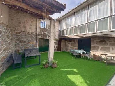 an outdoor patio with green grass and a table and chairs at A Casiña do Anselmiño in Celanova