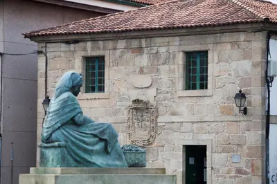 a statue of a woman sitting in front of a building at Nido PADRON in Padrón