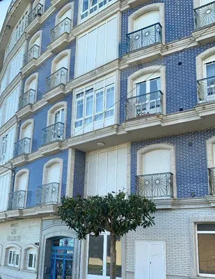 a blue brick building with a tree in front of it at El mirador del mar in Foz