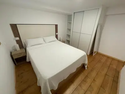 a bedroom with a white bed and a wooden floor at Apartamento Paseo Malecón Planta 1 in Monforte de Lemos