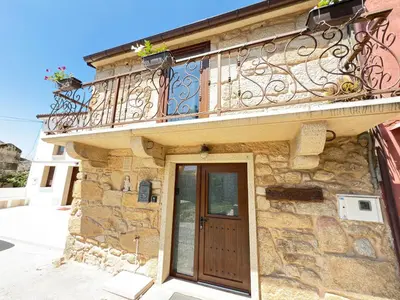a stone house with a balcony and a door at A de Pepita, Rural House in Padrón by URent in Padrón