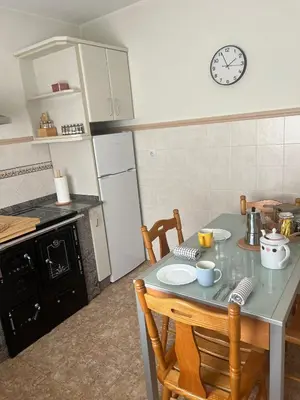 a kitchen with a table with chairs and a clock on the wall at Casa das Pasadiñas-Burela in Burela de Cabo