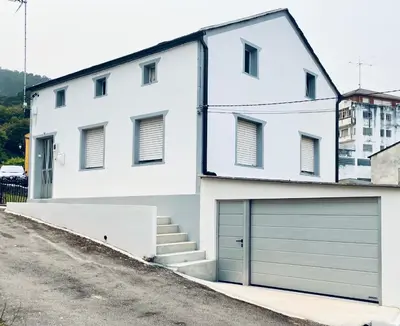 a white house with a garage at Casa das Pasadiñas-Burela in Burela de Cabo
