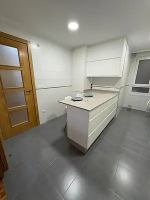 a kitchen with a white counter and a door at Piso Rente o Mar in Foz