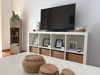 a white entertainment center with a tv and two stools at Piso Rente o Mar in Foz