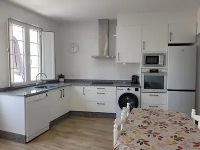 a kitchen with white cabinets and a table and a kitchen with a dishwasher at Vaniria 3 Apartamentos Nuevos in Foz