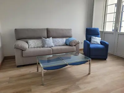 a living room with a couch and a blue chair at Vaniria 3 Apartamentos Nuevos in Foz