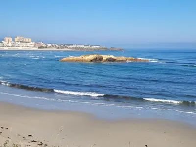 a beach with a rock in the middle of the ocean at Vaniria 3 Apartamentos Nuevos in Foz