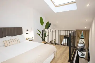 a bedroom with a white bed and a balcony at Dorian Suites in Monforte de Lemos