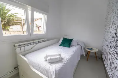 a small bedroom with a bed with a window at Villa Las Catedrales - Frente a la playa - Amplio jardín - Piscina in Barreiros