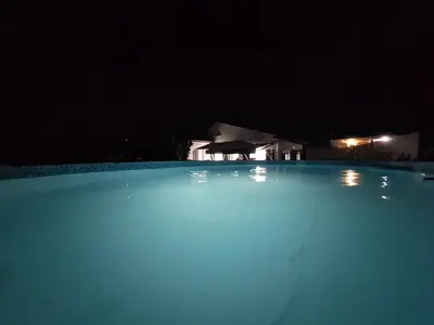 a swimming pool at night with a house in the background at Villa Las Catedrales - Frente a la playa - Amplio jardín - Piscina in Barreiros