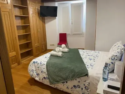 a bedroom with a bed with a red chair at Entrepraciñas A in Santiago de Compostela