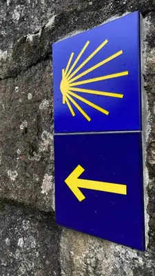 a blue sign with an arrow on a stone wall at Casa Aldea de Piñeiro, Turismo Rural Padrón by URent in Padrón