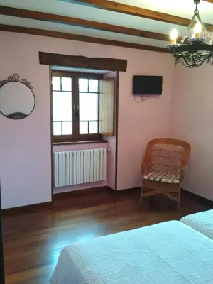 a bedroom with two beds and a tv and a chair at Casa Fonso in Villapedre