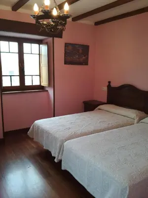 two beds in a bedroom with pink walls and a chandelier at Casa Fonso in Villapedre
