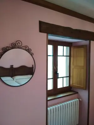 a mirror in a room with a bed and a window at Casa Fonso in Villapedre