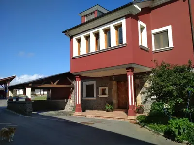a red house with a dog standing in front of it at Casa Fonso in Villapedre
