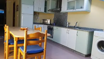 a kitchen with a table and a sink and a washing machine at Apartamento Ático Select Real Caldas de Reis in Caldas de Reis