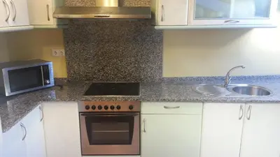 a kitchen with a sink and a stove and a microwave at Apartamento Ático Select Real Caldas de Reis in Caldas de Reis