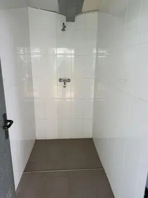 a bathroom with a shower with white tiles at ALBERGUE Pasiño A Pasiño in Portomarin