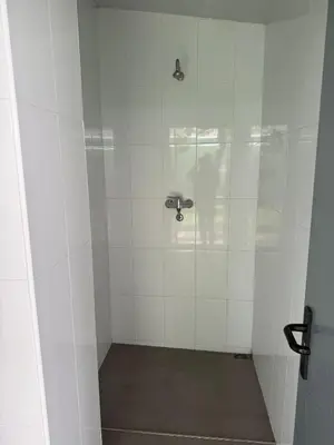 a bathroom with a shower with white tiles at ALBERGUE Pasiño A Pasiño in Portomarin