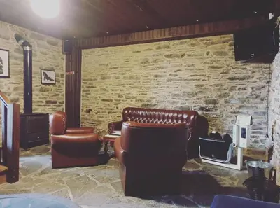a waiting room with leather chairs and a stone wall at ALBERGUE Pasiño A Pasiño in Portomarin