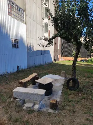 a park with benches and a tree next to a building at Cesarina Urban House in Chantada