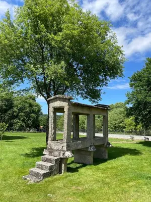 a stoneolith sitting in the grass under a tree at Vilaboa Paradise in Villanueva