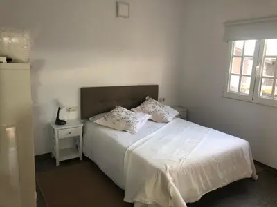 a bedroom with a bed with white sheets and a window at Cafú Casita in Coirós