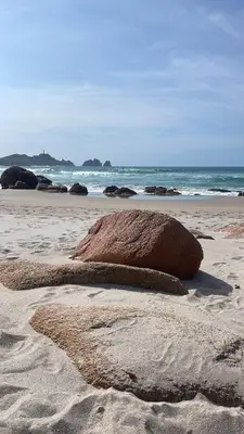 a large rock sitting on the sand on a beach at Cafú Casita in Coirós