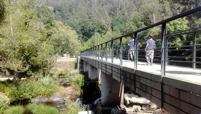 two people walking on a bridge over a river at Cafu loft in Coirós