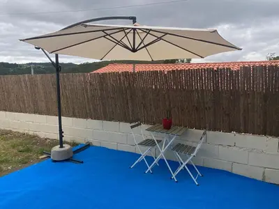 a table and chairs under an umbrella on a blue carpet at Cafu loft in Coirós