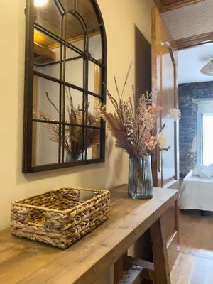 a table with a mirror and a vase with flowers at Go Compostela Apartamento 4 pax in Sarria