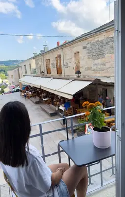 a woman sitting at a table looking out of a window at Go Compostela Apartamento 4 pax in Sarria