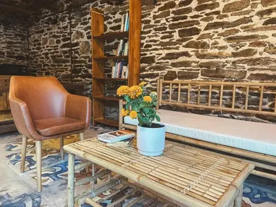 a chair and a bed and a table with flowers at Go Compostela Apartamento 4 pax in Sarria