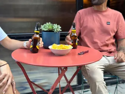two people sitting at a red table with beer at Go Compostela Apartamento 4 pax in Sarria