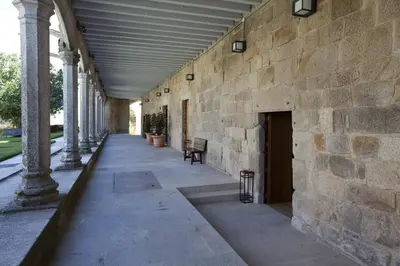 an empty hallway with a stone building with columns at Parador Castillo de Monterrei in Monterrei