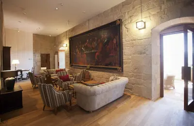 a living room with a large painting on a stone wall at Parador Castillo de Monterrei in Monterrei
