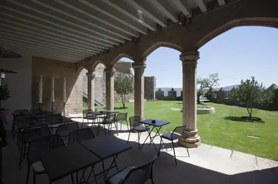 a patio with tables and chairs and a view of a yard at Parador Castillo de Monterrei in Monterrei