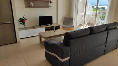 a living room with a black couch and a television at Apartagal-Océano V Barreiros in Barreiros