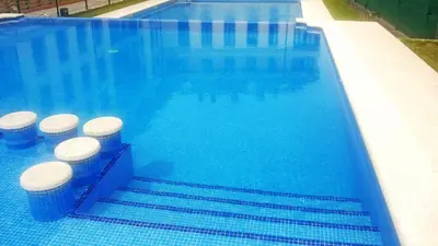 a swimming pool with blue water and fourools in it at Apartagal-Urbanización Foz II in Foz