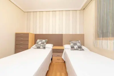 two twin beds in a room with wooden floors at Apartagal-Urbanización Foz II in Foz