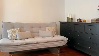 a white couch with two pillows sitting next to a dresser at VIVIENDA OLGA, piso tranquilo con parking a 10 min de Santiago in Sigüeiro